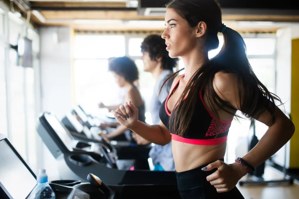 Group of people running on treadmills in a gym, focusing on endurance training to improve their stamina and overall fitness.