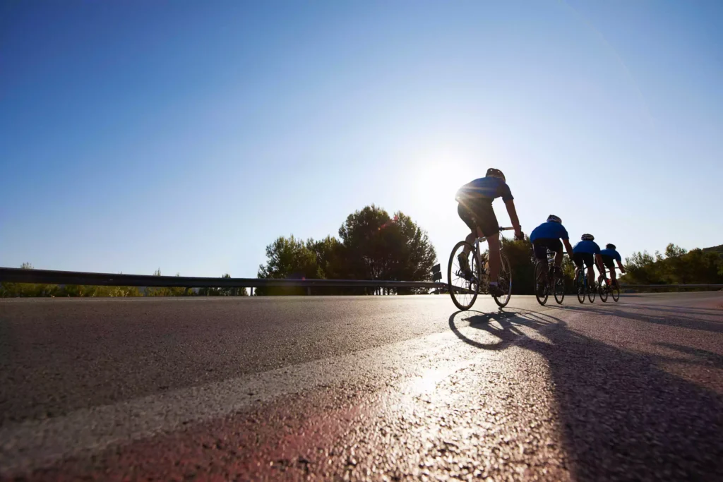 Cyclists riding on a sunlit road, focusing on measuring normalized power during their workout.