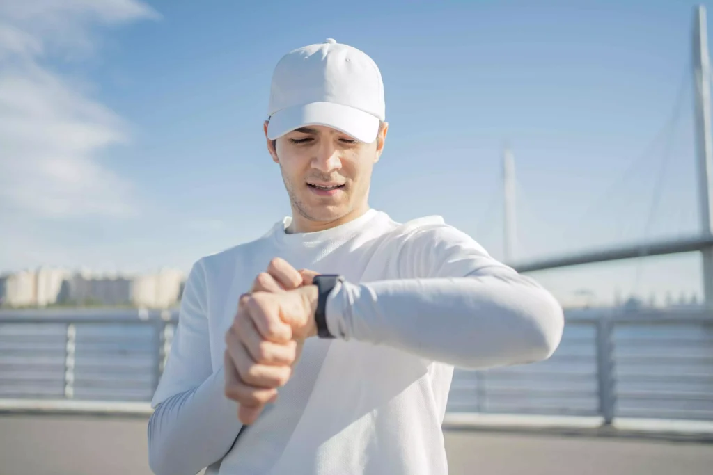 Runner checking smartwatch to track heart rate and pace decoupling during endurance training.