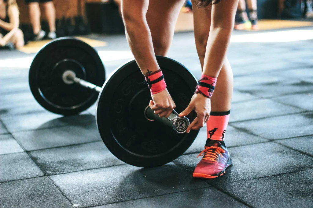 Person preparing a barbell for a workout, focusing on managing Acute Training Load to avoid overtraining.